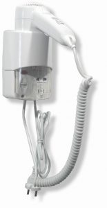 Per una maggiore comodità in bagno, è installato accanto a un asciugamano elettrico un piccolo asciugacapelli a pistola per hotel con attacco, un asciugacapelli bianco da parete con cavo a spirale e spina su una base rettangolare.