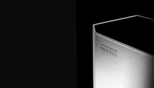 Primo piano di un elegante dispenser di sapone metallico con la parola mediclinics incisa, su uno sfondo nero con un'illuminazione spettacolare che ne evidenzia i bordi.
