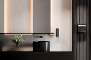 Bagno moderno con lavandino nero, un vaso di verde, ampi armadietti a specchio e un'elegante illuminazione. Sulla destra, un dispenser di sapone e un dispenser di carta mani completano l'arredamento minimalista e contemporaneo.