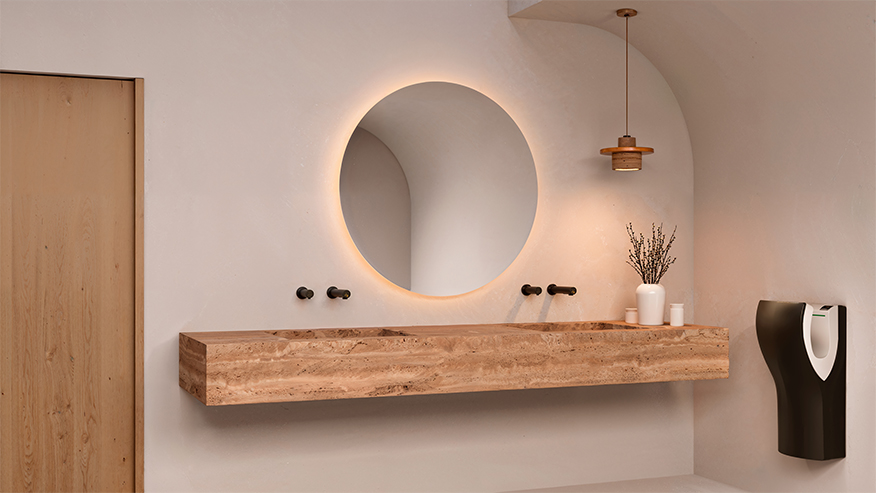 Bagno moderno e minimalista con specchio rotondo retroilluminato, bancone del lavabo in legno galleggiante, rubinetteria nera a parete, piccolo vaso con lavanda, luce a sospensione e dispenser di sapone in bianco e nero su una parete beige.